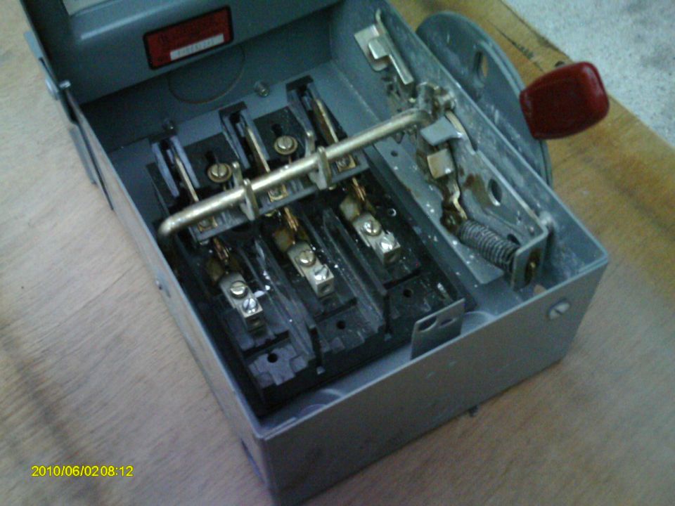 Open electrical box with a lever and three knife switches inside