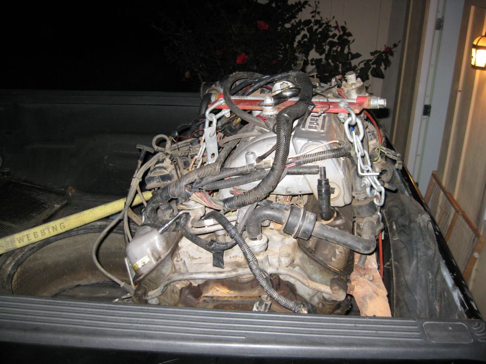 Engine assembly with chains and hoses, resting in a truck bed