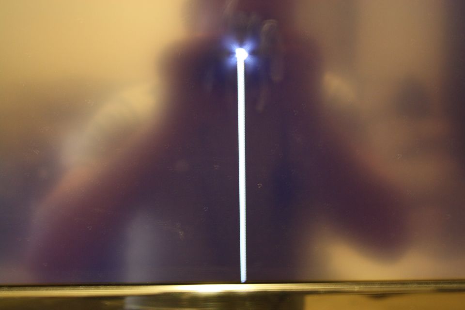 Reflection on a dark screen with a bright vertical line and a person's silhouette
