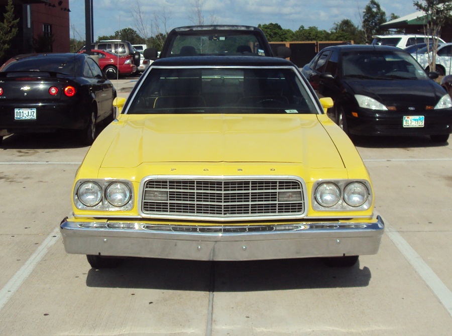 Front of a yellow 1970s Ford coupe in a parking lot