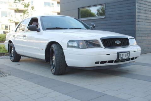 1998 Ford Crown Victoria - A white 1998 Ford Crown Victoria sedan is shown from a three-quarter front angle.
