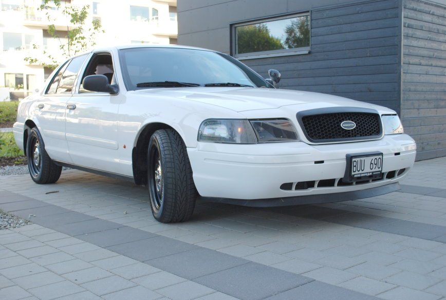 White 1998 Ford Crown Victoria sedan with black wheels parked on a paved driveway