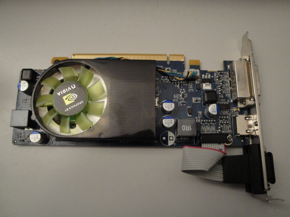 Nvidia graphics card with green fan and heatsink, connected by ribbon cable
