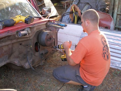 1969 Ford F-250 - A person is drilling into the firewall of a vehicle while a reciprocating saw rests on the fender.