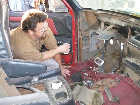 1969 Ford F-250 - A man sits in the driver's seat of a truck with its interior disassembled, revealing exposed wiring and components.