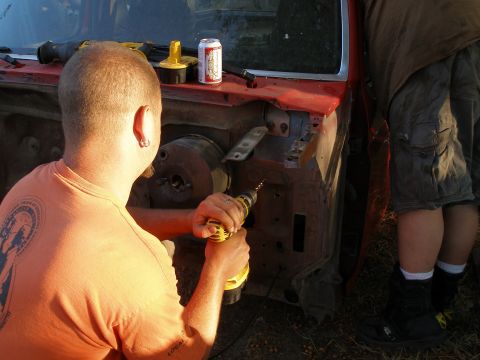 1969 Ford F-250 - A man drills into the engine bay of a red vehicle, possibly during a body swap or repair.