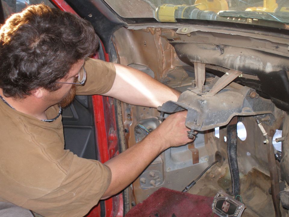 Man working on the dashboard and steering column area of a vehicle interior