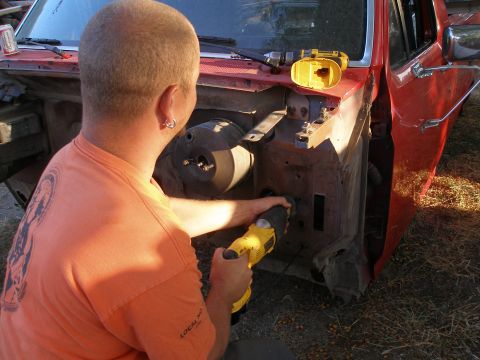 1969 Ford F-250 - A person is working on the engine bay of a red vehicle with power tools.