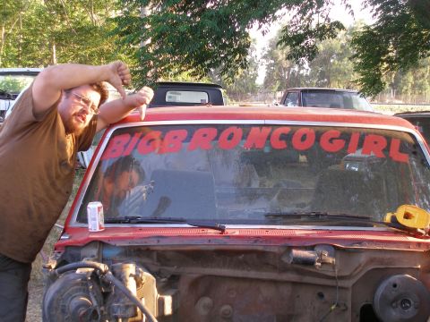 1969 Ford F-250 - Man expresses disapproval while leaning on a red truck with custom windshield text.