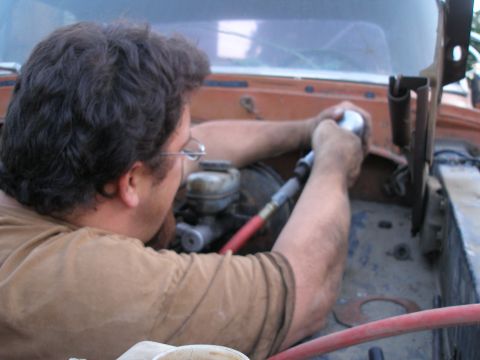 1969 Ford F-250 - Mechanic works on the engine bay of an orange truck, focusing on the brake system.