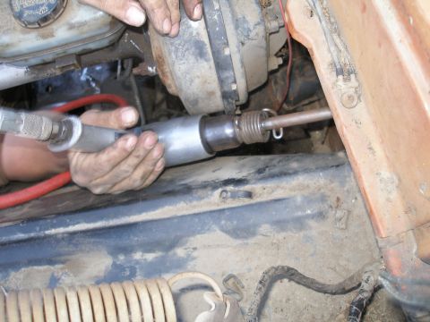 1969 Ford F-250 - Close-up of a mechanic's hands working on a vehicle's engine with a tool.