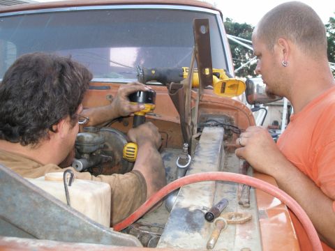1969 Ford F-250 - Mechanics are performing maintenance or repairs on the engine of a vehicle.
