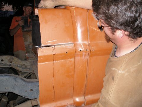 1969 Ford F-250 - Two men work on the side of an orange truck cab, possibly modifying it for a body swap.