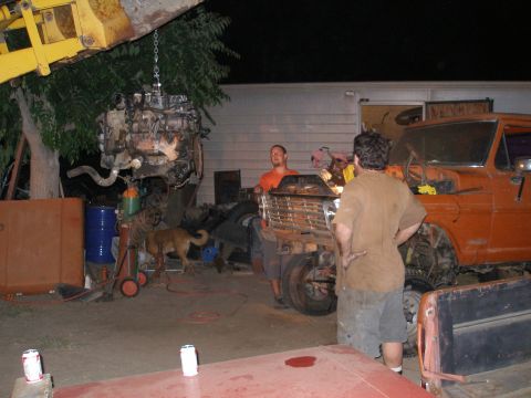 1969 Ford F-250 - An engine is being removed from an orange Ford truck in a yard at night, with two men and a dog present.