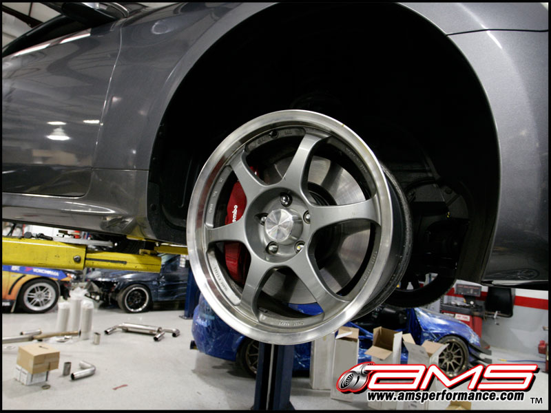 Gray multi-spoke wheel with red Brembo brake caliper on a lifted car