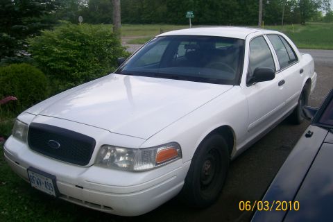2001 Ford Crown Victoria - White 2001 Ford Crown Victoria, front 3/4 view, parked outdoors next to another vehicle.