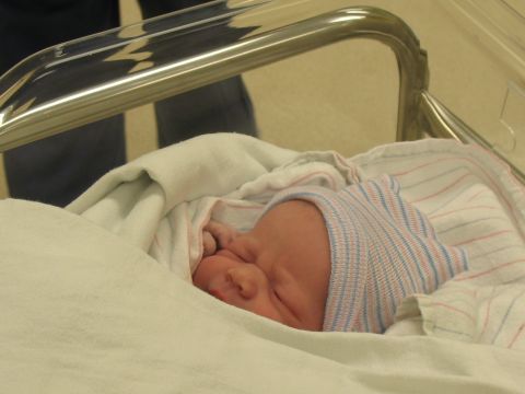 2001 Pontiac Trans Am - A newborn baby sleeps soundly in a hospital bassinet, wearing a striped hat and swaddled in blankets.