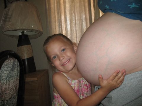 2001 Pontiac Trans Am - A child embraces a pregnant belly, with a lamp and curtains in the background.