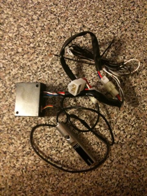 2005 Subaru Impreza - A car alarm remote and its control module are shown, connected by wires, on a speckled surface.