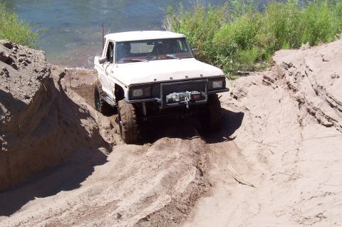 1981 Ford F-150 - Ford pickup truck driving through sand and water on an off-road trail.