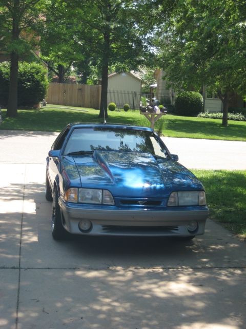 1990 Ford Mustang - A blue 1990 Ford Mustang is parked in a suburban driveway on a sunny day.