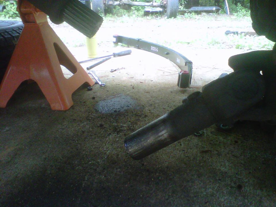 leaf spring with 'JBH' marking and exhaust pipe under a vehicle
