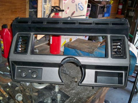 1985 Ford Bronco - Dashboard trim piece with vents and knobs, likely for an older vehicle, on a workbench.
