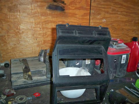 1985 Ford Bronco - A disassembled dashboard trim piece is shown, with various items like batteries and tools in the background.
