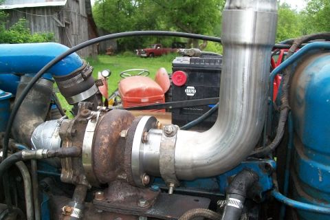 2000 Chevrolet Tahoe - Close-up view of a turbocharger and exhaust system installed on a tractor engine, with a NAPA battery in the background.