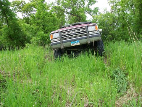 1988 Ford F-150 - 1988 Ford F-150 navigates a grassy incline, showing its front grille and license plate.