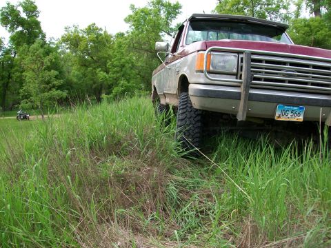 1988 Ford F-150 - A 1987 Ford F-150 truck is parked off-road, with a motorcycle visible in the distance.
