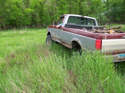 1988 Ford F-150 - This 1988 Ford F-150 is seen from the side, parked in a grassy field with wood in its bed.