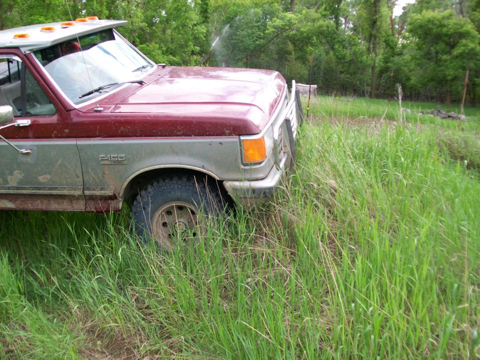 Red and gray 1987 Ford F-150 pickup truck in tall grass