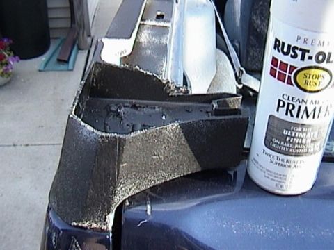 1995 Ford Bronco - Spray primer can sits next to a vehicle bumper part being prepped for painting.