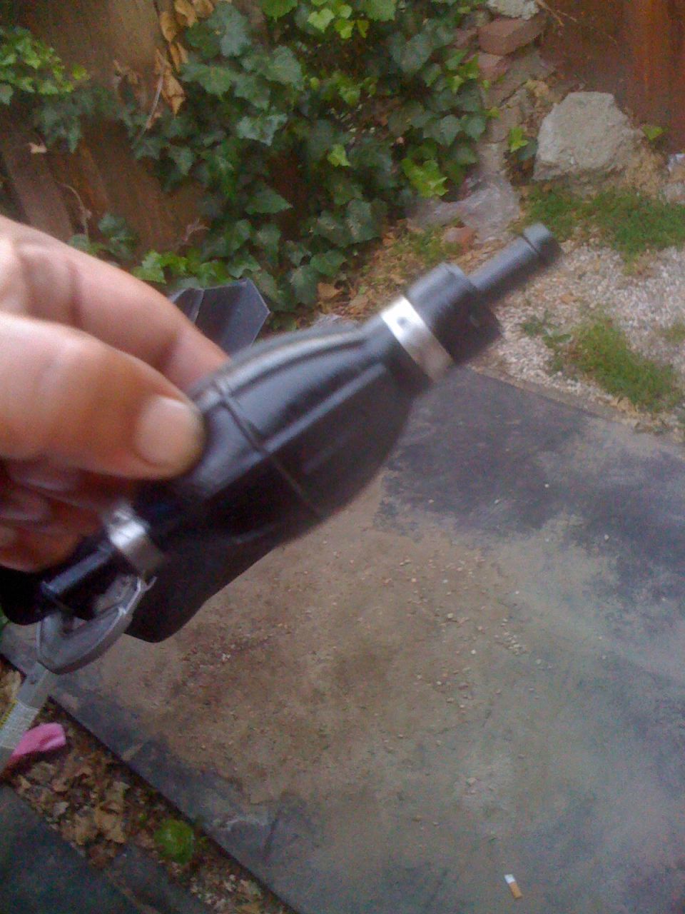 Hand holding black fuel primer bulb with silver bands