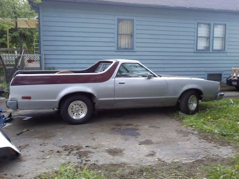 1979 Ford Ranchero - A silver 1979 Ford Ranchero with maroon trim is parked in a driveway next to a blue house.