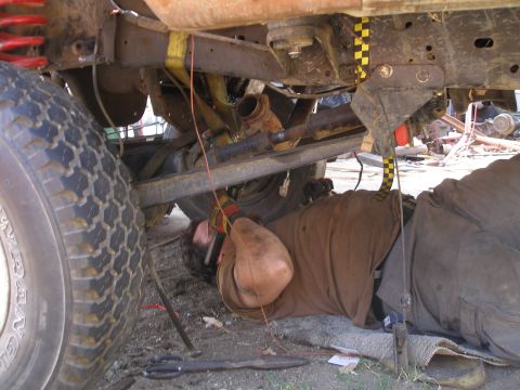 1969 Ford F-250 - A mechanic works on the underside of a vehicle, focusing on the suspension and drivetrain components.