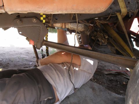 1969 Ford F-250 - A mechanic works on the underside of a vehicle, examining its suspension and frame components.