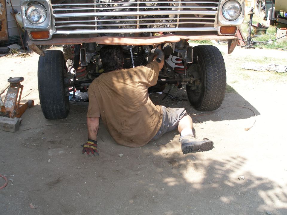 Truck front end with grille and headlights, mechanic working underneath