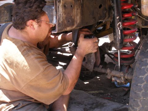 1969 Ford F-250 - Mechanic adjusts suspension components on a truck, focusing on the spring and shock assembly.