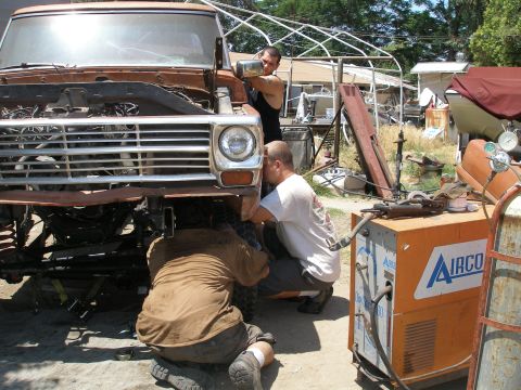 1969 Ford F-250 - Mechanics work on a truck's front end, with a welding machine and various parts in the background.