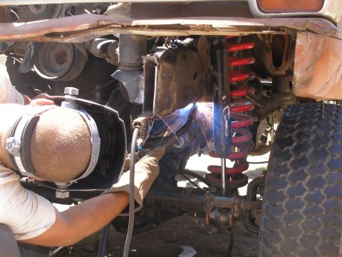 1969 Ford F-250 - A person in a welding mask works on the suspension system of a vehicle, with bright sparks flying.
