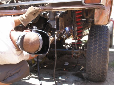 1969 Ford F-250 - Welding is performed on the frame of a vehicle, with a focus on the suspension and tire.