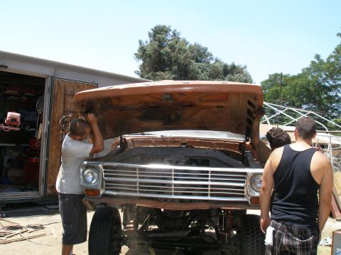 1969 Ford F-250 - Mechanics work on the front end of a rusty orange Ford F-Series truck.