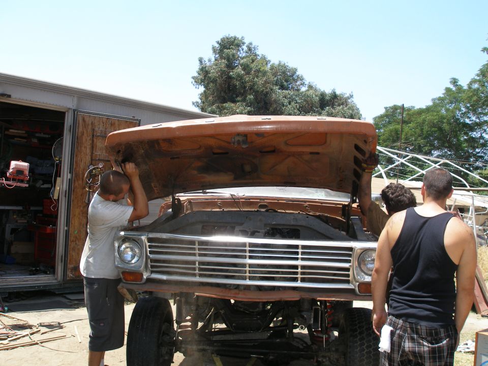 Orange Ford F-Series truck with hood open, undergoing repairs