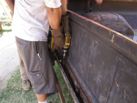 1969 Ford F-250 - A person drills into the side of a weathered truck bed, revealing its internal structure.