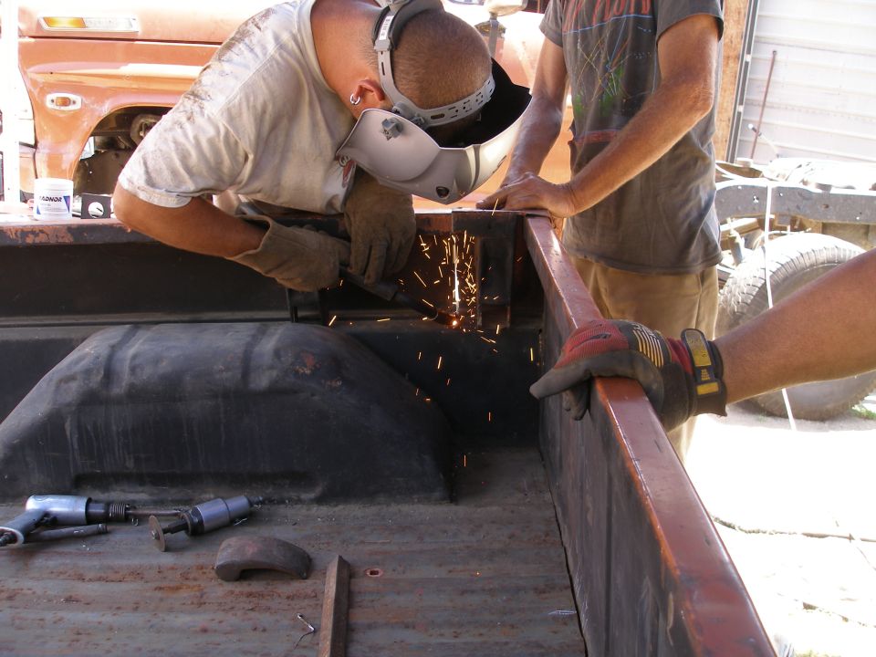 1969 Ford F-250 truck bed being welded by a person wearing a welding mask