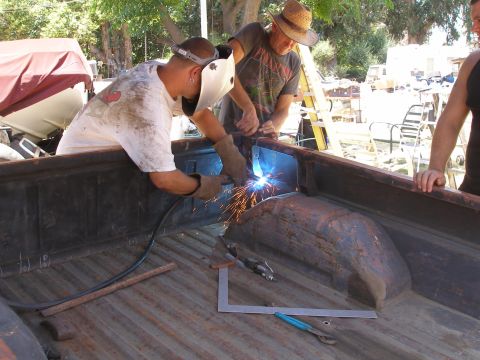 1969 Ford F-250 - Two men are welding metal inside the bed of a pickup truck during a repair.