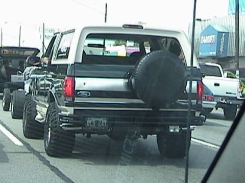 1995 Ford Bronco - Rear view of a modified Ford Bronco driving on a street with a Target store in the background.