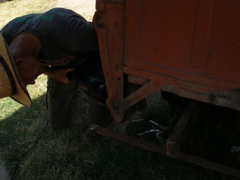 1969 Ford F-250 - A man works on the side of a rusty orange truck bed, possibly a 1967 Ford F-100.